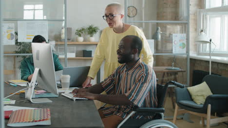 Black-Businessman-in-Wheelchair-Working-with-Female-Colleague-in-Office